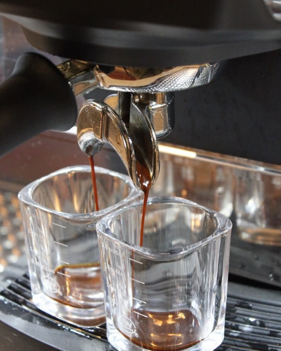 A double espresso shot pulling into two glasses