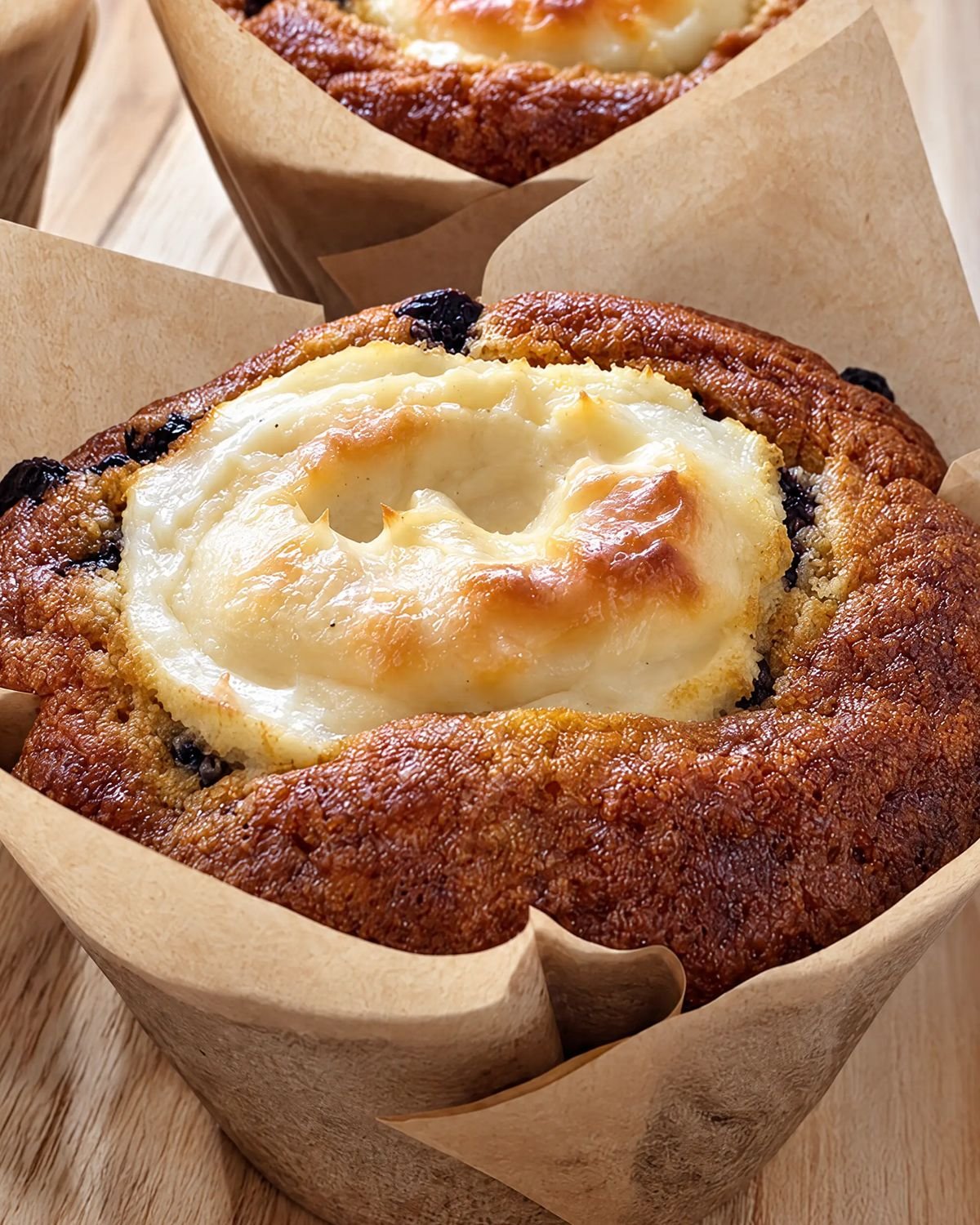 A blueberry muffin with a baked creamy center in a brown paper tulip wrapper