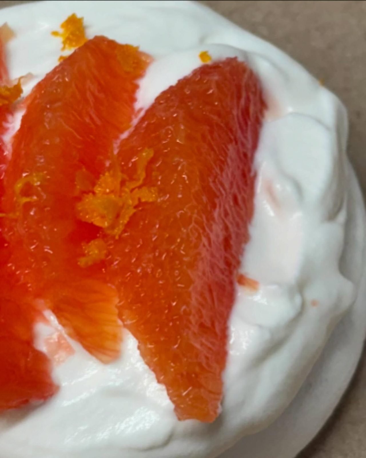 A pavlova topped with cream and blood orange